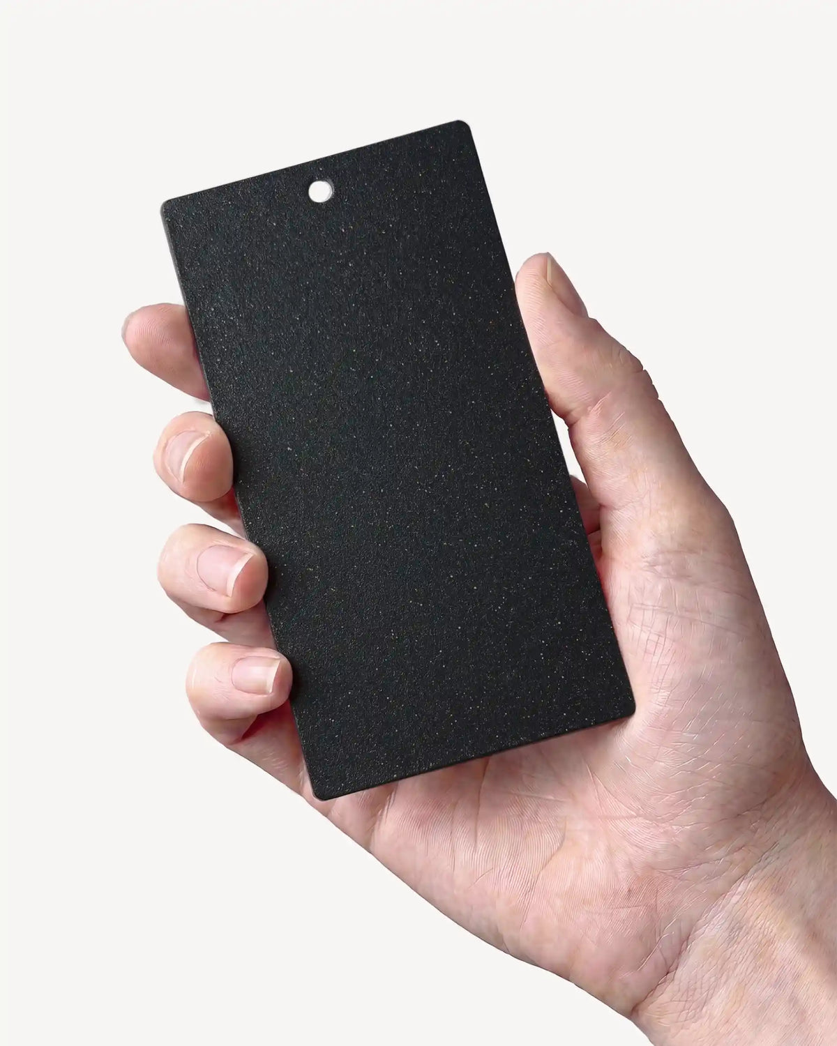 Hand, das ein Muster in der Farbe Tiefschwarz PILOTIS hält