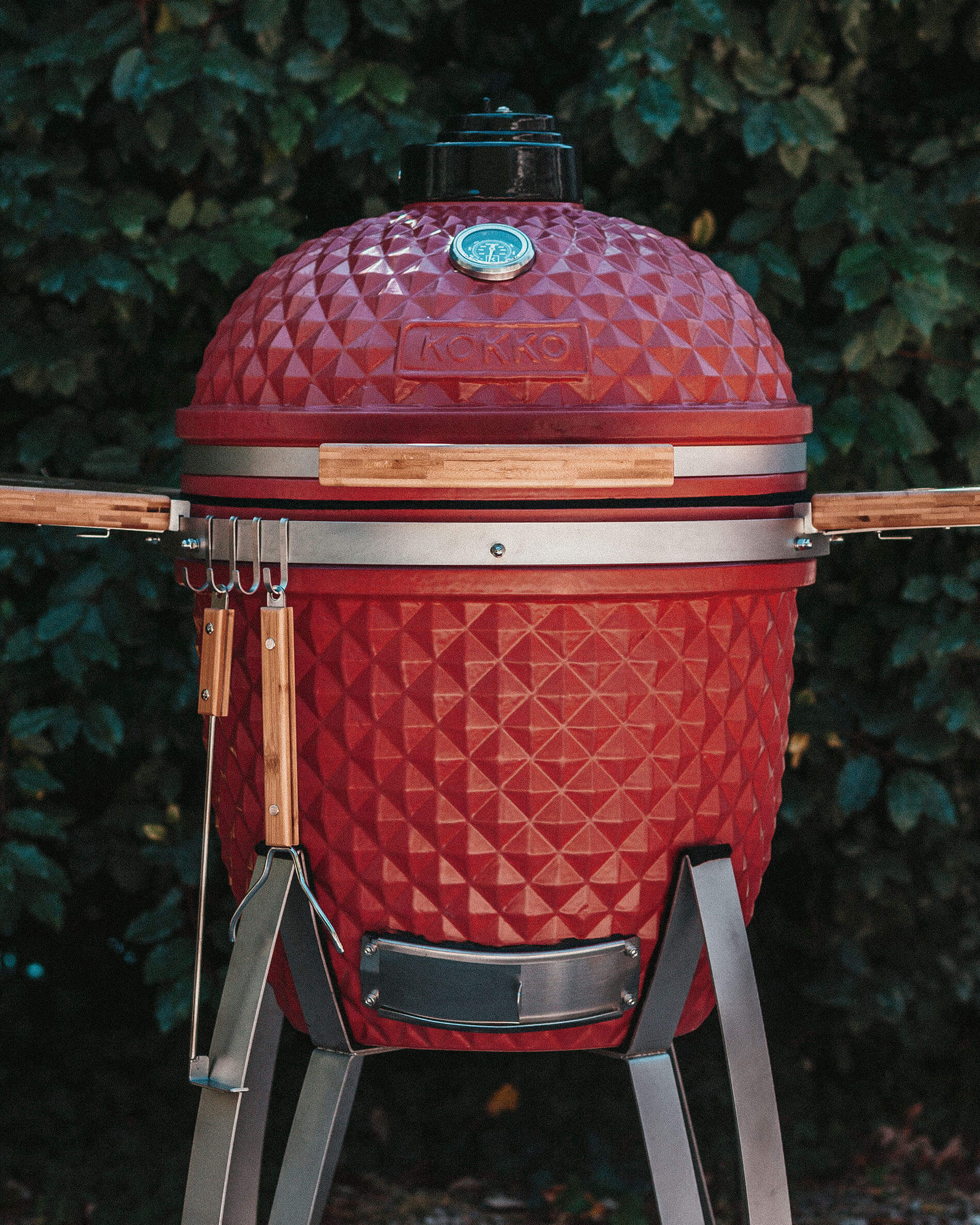 Kamado Kokko rouge équipé de crochets pour accessoires.