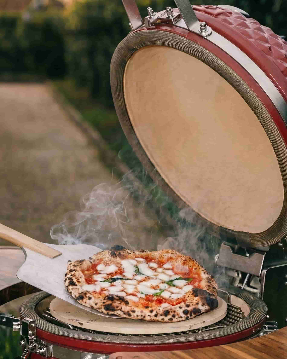 Pizza auf einem Schamottstein im geöffneten Kokko Kamado, gegart über Holzkohle.