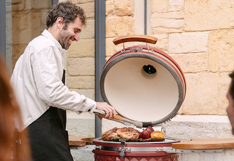 Kokko-Experte demonstriert im Freien die besten Grilltechniken mit einem roten Oxid-Kamado.