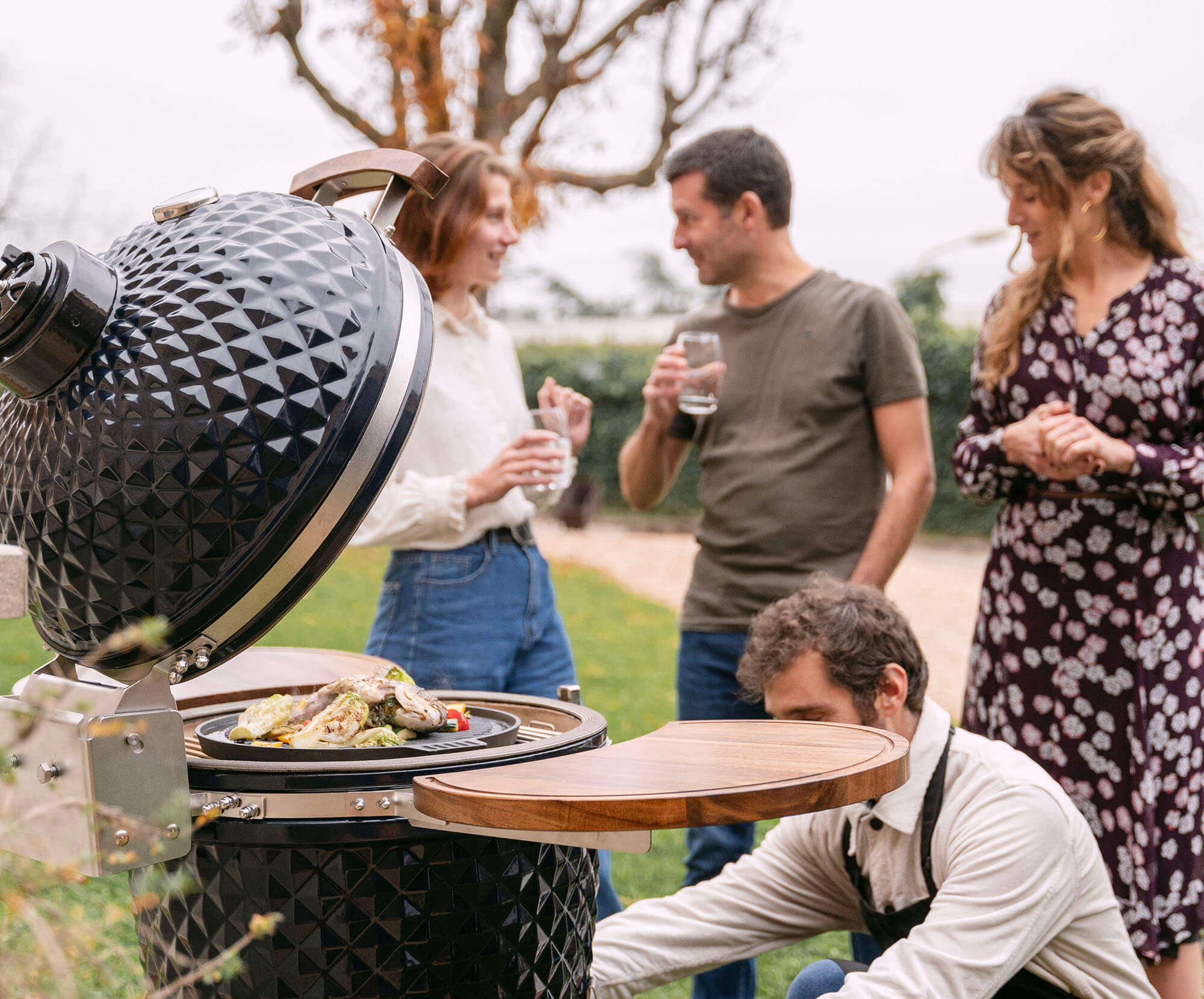 Kamado Kokko neue Edition im Einsatz, mit Speisen während des Garens – Sinnbild für Geselligkeit und erstklassige Grill-Performance.
