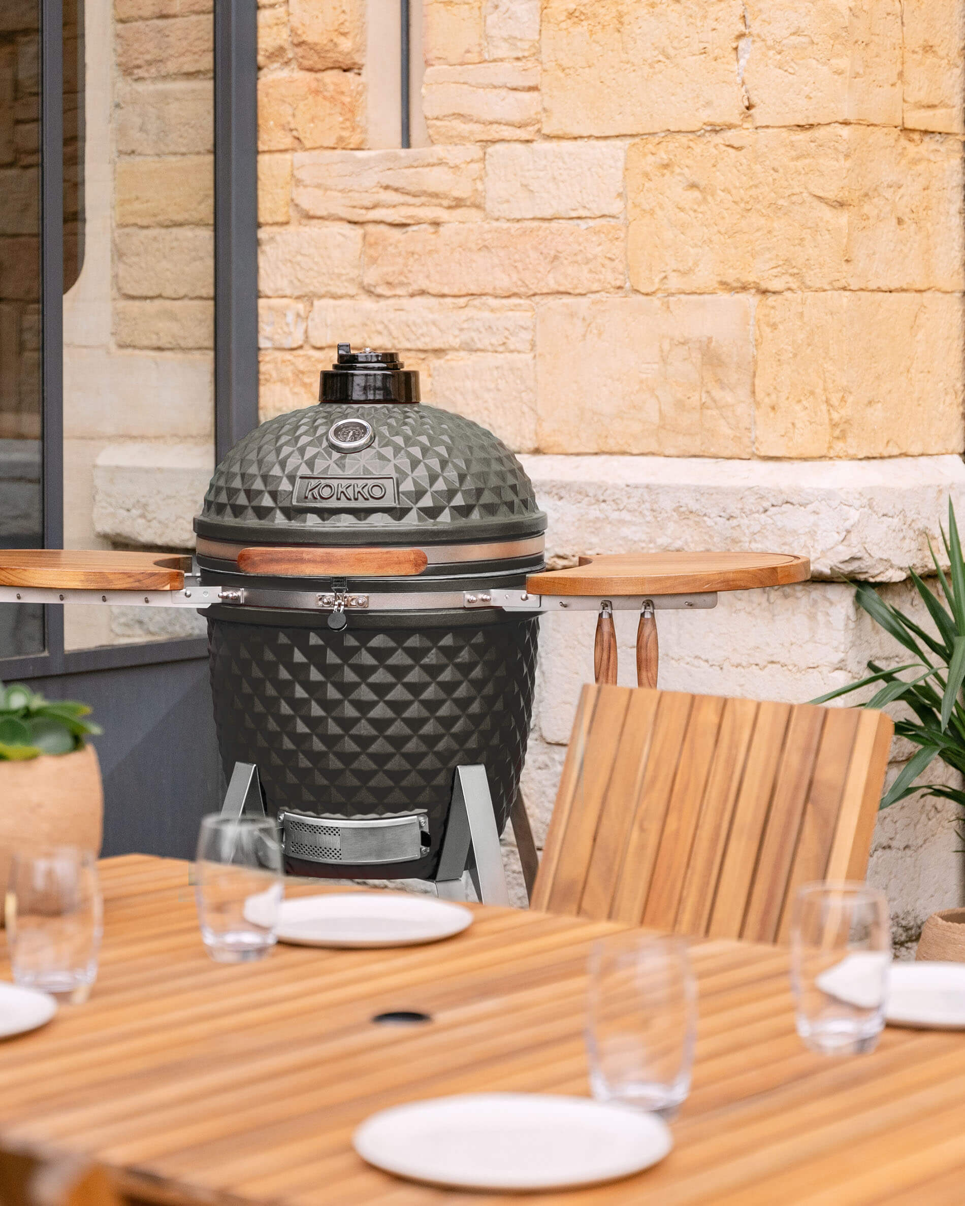 Kamado Kokko 22 pouces en céramique vert olive présenté sur une terrasse.