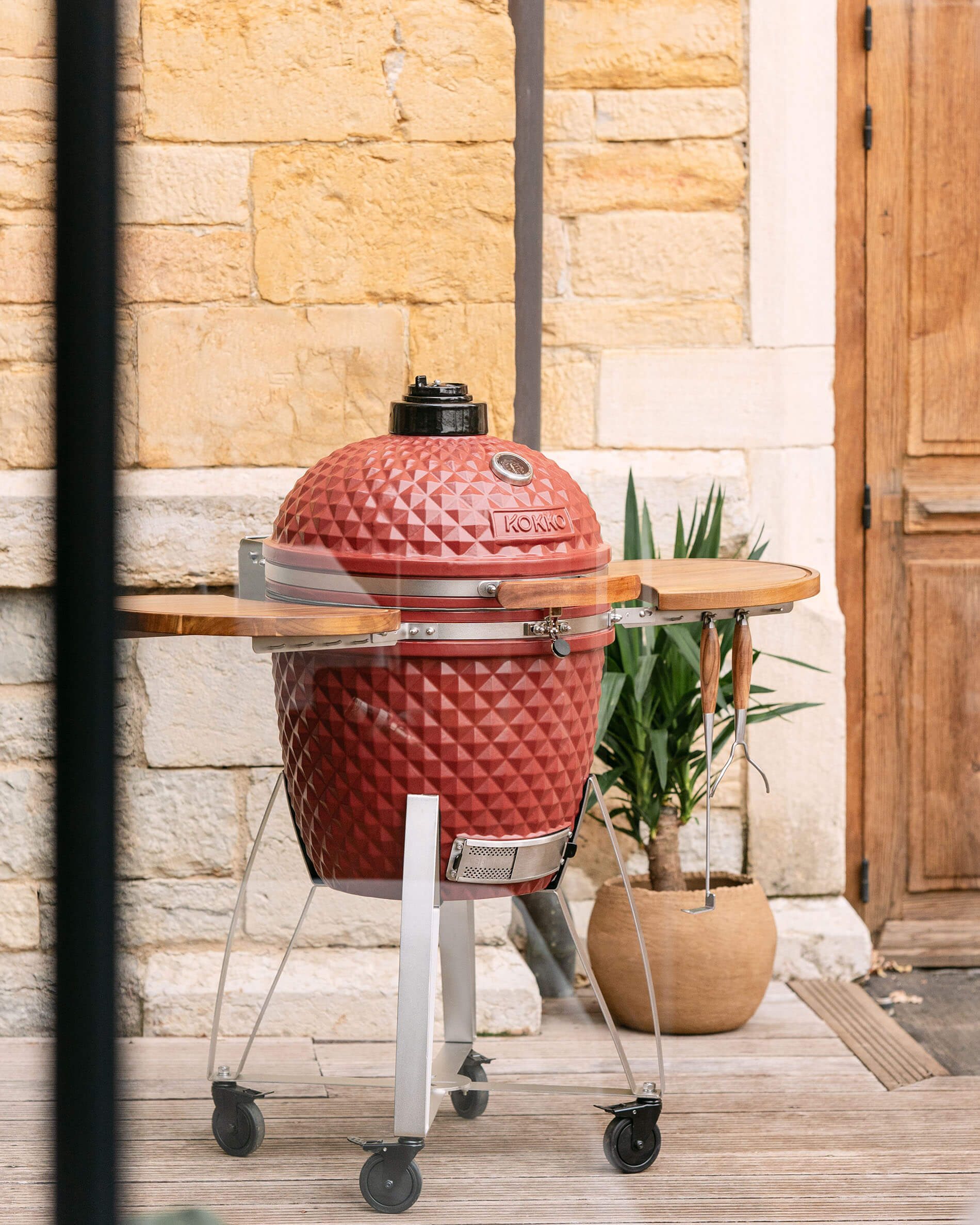 Kamado Kokko XL 22 pouces en céramique rouge oxyde installé sur chariot en extérieur.
