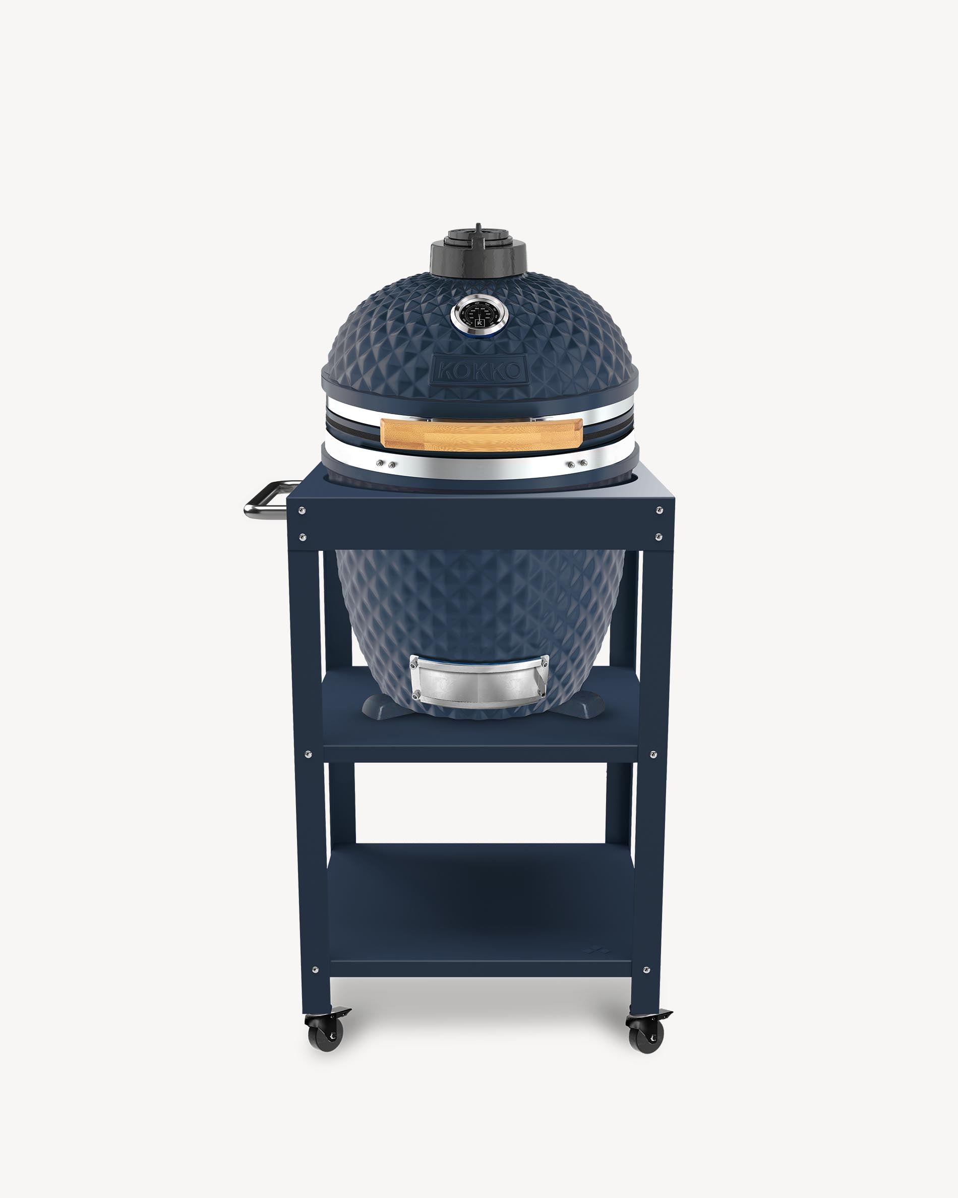 Barbecue kamado Kokko L 18 pouces coloris navy, installé sur desserte avec rangements et roulettes.