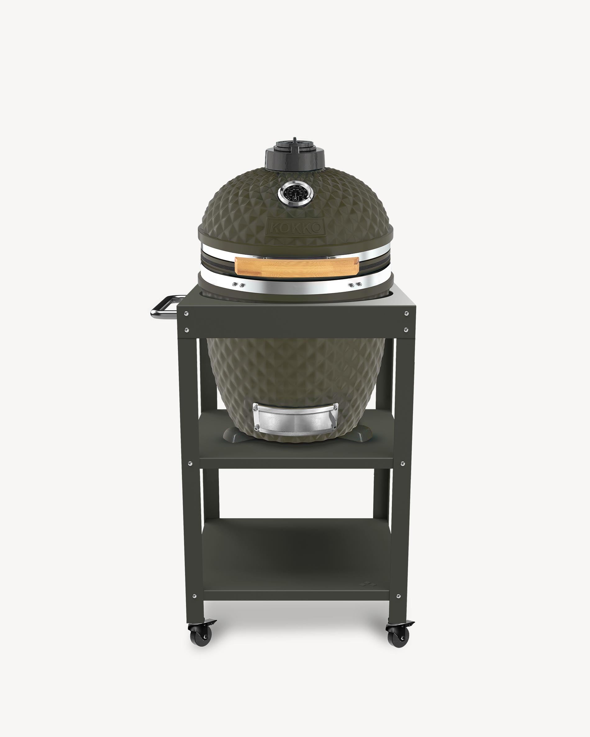 Barbecue kamado Kokko L 18 pouces coloris olive, installé sur desserte avec rangements et roulettes.