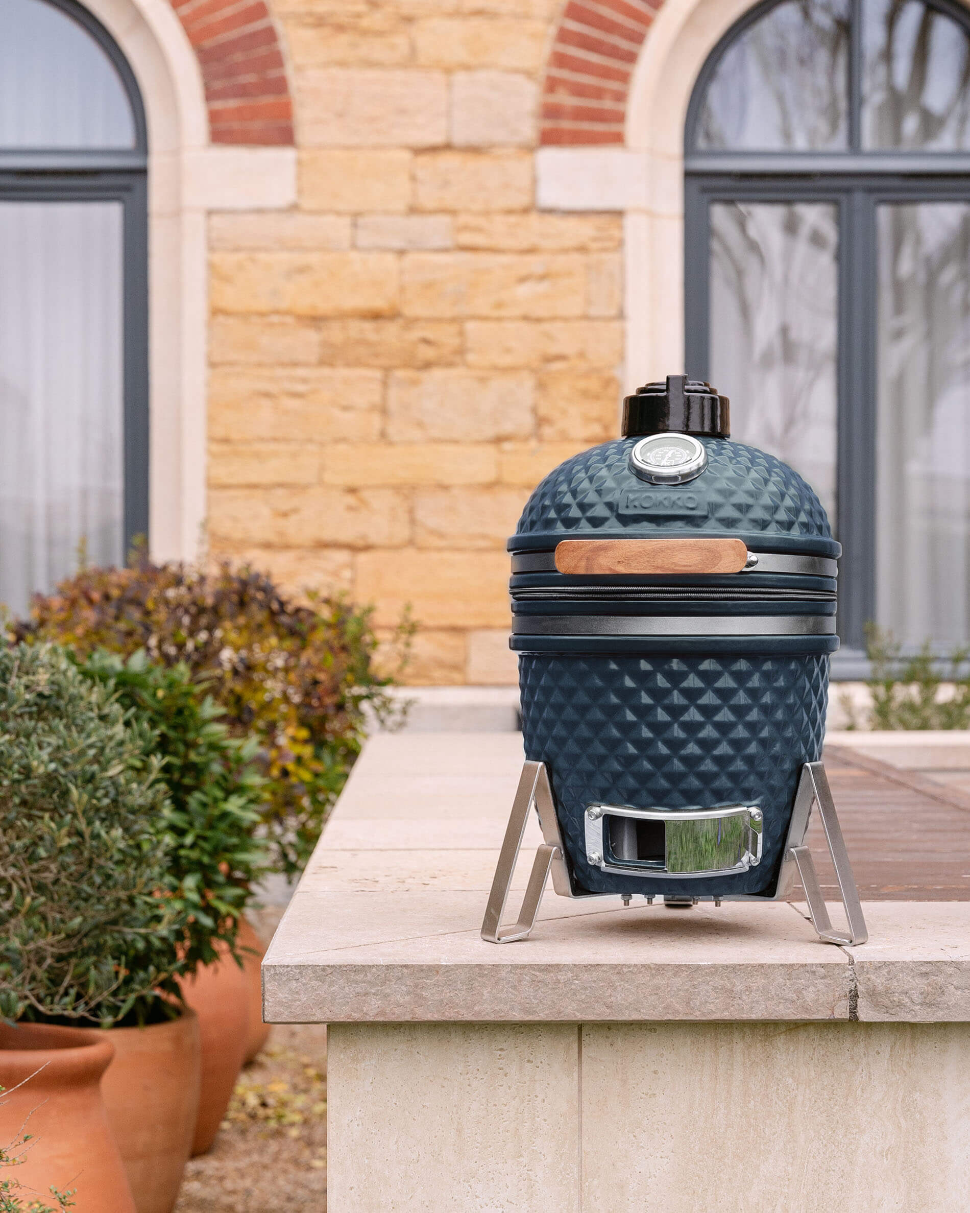 Kamado Little Kokko 13 en céramique bleu océan, installé en extérieur.