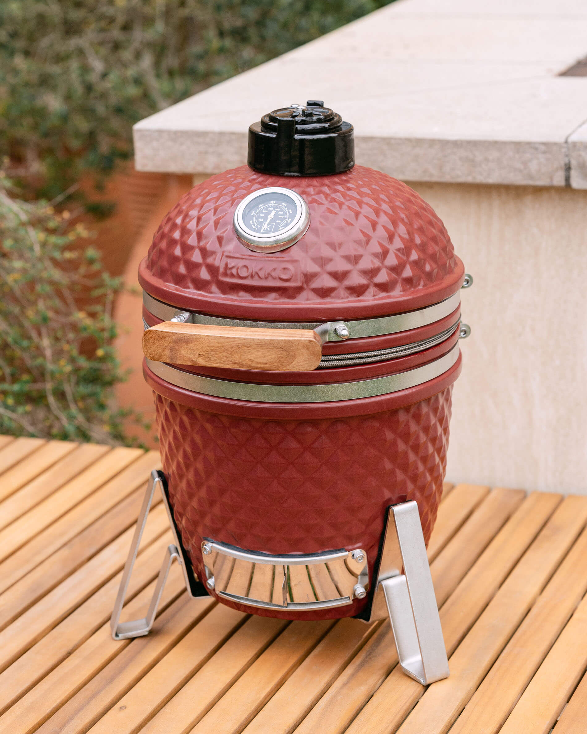 Kamado Little Kokko 13 rouge oxyde installé sur une terrasse.