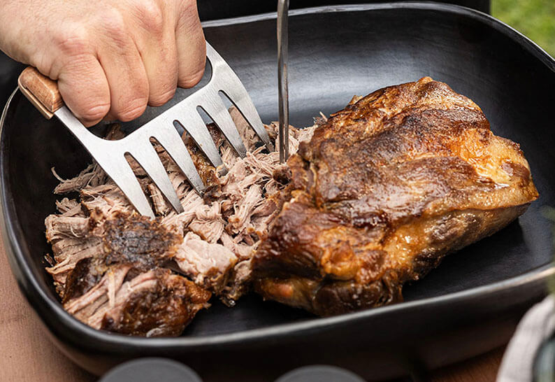 Porc effiloché cuit au kamado Kokko, effiloché à l’aide d’une paire de griffes au-dessus de la grille.